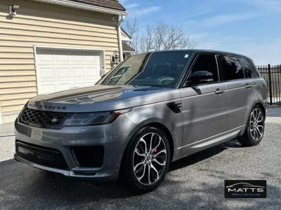 A technician using a rotary polisher to perform a paint correction on the side panel of a dark vehicle.